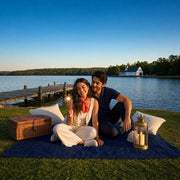 Couple watching a sparkler burst on a lakeside picnic blanket at sunset, Fourth of July experience gift