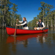 Red canoe gliding between cypress trunks on a still river, Canoeing experience gift