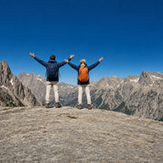 Two hikers with arms raised on a granite summit ridge, Adventure experience gift