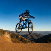 Rider launching off a dirt ridge jump with both wheels up, All Action experience gift