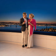 Couple toasting cocktails at a rooftop rail above the bay bridge lights, Anniversary in San Francisco experience gift