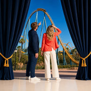 Couple pointing at a roller coaster cresting at a sunlit theme park, Attraction Pass experience gift