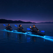 Three kayaks trailing glowing cyan wakes across a night bay, Bioluminescence Kayak Tour experience gift