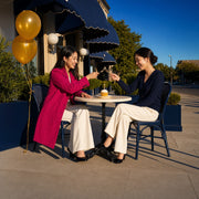 Two friends clinking dessert forks over a birthday cupcake at a cafe terrace, Treat Yourself experience gift