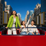 Friends on an open-top double-decker bus passing theater marquees, New York City Bucketlist Experience Collection gift