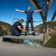 Jumper standing arms wide at the bridge edge as an operator checks his cuffs, Bungee Jumping experience gift