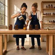 Maker pouring molten wax into a row of jars in a sunlit atelier, Candle & Perfume Making experience gift