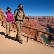 Couple hiking single file along a rim trail above a rust-red gorge, Canyon & Gorge Hikes experience gift