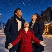 Child catching snowflakes between parents on a snowy street, Christmas Magic experience gift
