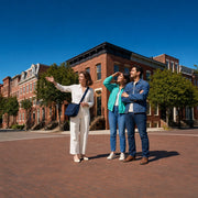 Guide pointing out historic facades to a couple on a brick corner, City Walking Tours experience gift