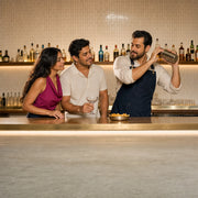 Instructor shaking a cocktail at the bar as a couple waits with a coupe glass, Cocktail Making Class experience gift