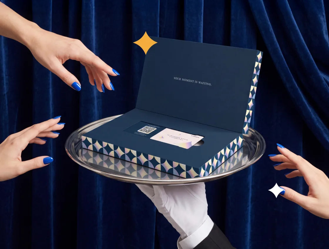 Hands reaching for an open Everwow experience gift box on a silver tray