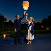 Couple releasing a glowing paper lantern on a garden terrace at dusk, It's Magic experience gift