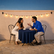 Couple laughing across a cafe table under warm bulb lights at dusk, Date Night Experiences experience gift
