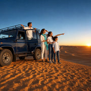 Family watching the sunset from a dune crest beside their 4x4, Desert Safari experience gift