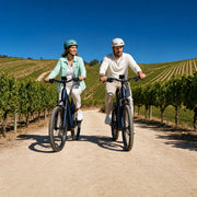 Couple riding e-bikes along a dirt path through vineyard hills, E-Bike Tours experience gift