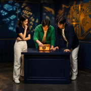 Three friends solving a glowing puzzle box in an escape room, Escape Quest experience gift