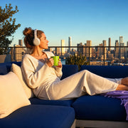 Woman with headphones and a mug, feet up on a balcony lounge, Off Duty experience gift