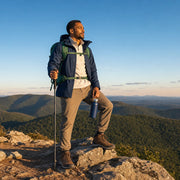 Hiker surveying forested hills from a ridge with a trekking pole, Outdoor Adventure experience gift