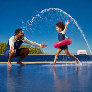 Child charging through a water jet at a splash pad as a parent laughs, Splish Splash experience gift