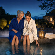 Mother and adult daughter with feet in a thermal pool by lantern light, Sweet Escape experience gift