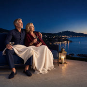 Couple under a throw with champagne on a coastal terrace at dusk, Second Honeymoon experience gift