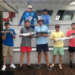 Group of anglers holding up their catch on the deck of a fishing charter boat
