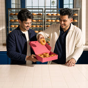 Two friends filling a box from a wall of glazed donuts, Donut tour experience gift