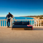 Couple leaning together at a sea-view terrace rail above turquoise water, Romantic Escape experience gift