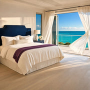 Suite with a linen bed and sheer curtains at a balcony over turquoise water, Suite Dreams experience gift