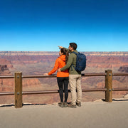 Couple at the Grand Canyon rim taking in the layered red rock, Grand Canyon National Park Tour experience gift