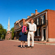 Guide pointing out a colonial facade to a visitor on a brick sidewalk, History & Heritage Tours experience gift
