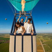 Pilot firing the burner as a couple looks over patchwork farmland from the basket, Hot Air Balloon Rides experience gift