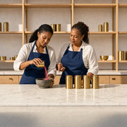 Student pouring ground spice into a stone mortar in a sunlit kitchen studio, Indian Cooking Class experience gift