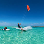 Kitesurfer skimming turquoise shallows under a coral kite, Kitesurfing & Wakeboarding experience gift