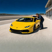 Student at the wheel of a yellow supercar as an instructor points down the track, Lamborghini Driving experience gift