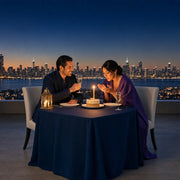 Couple celebrating a birthday at a rooftop table, one candle on the cake, Iconic Make a Wish Luxe experience gift