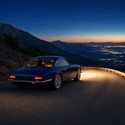 Driver guiding a sapphire grand tourer along a mountain road at dusk, Iconic Thrill rides Luxe experience gift