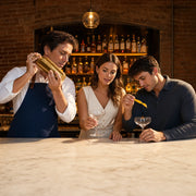 Instructor shaking cocktails with a couple at a marble bar, Mixology & Cocktail Classes experience gift