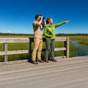Guide and visitor with binoculars looking over green wetland from a boardwalk, Nature & Wildlife Walk experience gift