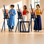 Three friends painting at easels with wine glasses waiting nearby, Paint & Sip Class experience gift