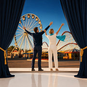 Couple cheering toward a ferris wheel at a fairground at sunset, Iconic Attraction Pass experience gift