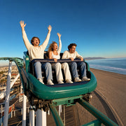 Three friends cresting a boardwalk coaster above the beach, hands raised, Los Angeles Iconic Bucketlist experience gift
