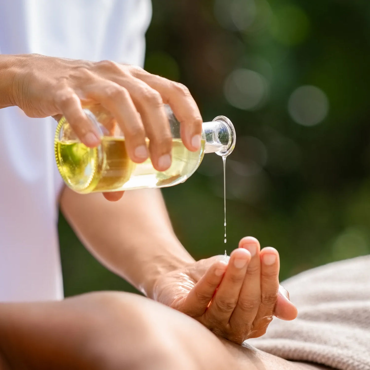 Therapist pouring warm aroma oil into their hand during a relaxing spa massage