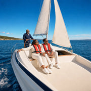 Couple relaxing aboard a white sloop as their skipper holds the tiller, Sailing Cruises experience gift