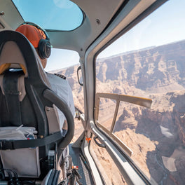 View from a helicopter cabin across layered canyon walls on a scenic flight