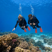 Two divers hovering over a sunlit coral reef trailing bubbles, Scuba Diving experience gift