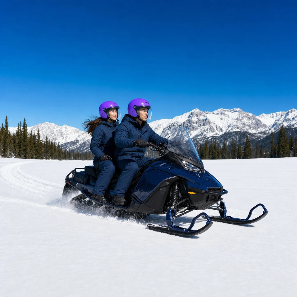 Couple riding a snowmobile across an open snowfield toward pines, Snowmobiling experience gift