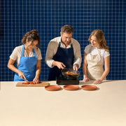 Instructor shaking a sizzling pan as students chop peppers in a tapas class, Tapas Cooking Class experience gift