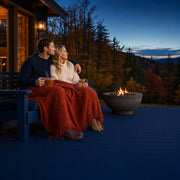 Couple sharing cider under a throw on a cabin deck at dusk, November Retreat experience gift